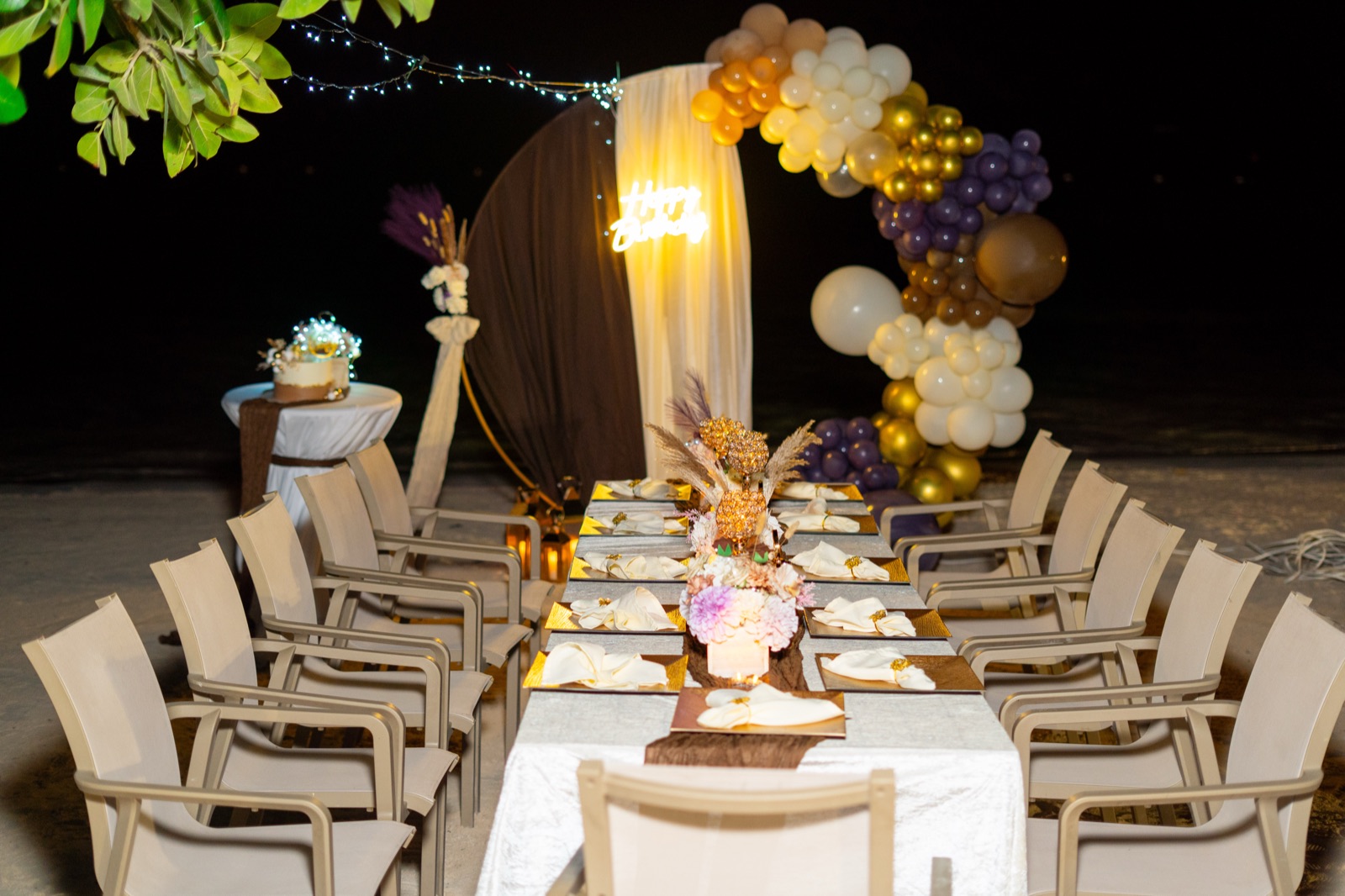 Beachside dinner table beneath a balloon arch at night